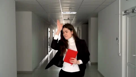 Energetic female with red notebook dancing in hallway of office building Stock Footage 240619987