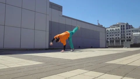 Energetic guy dancer breakdancing outdoors and standing on hand in the city Stock Footage 295069139