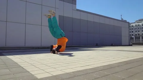 Energetic guy dancer breakdancing outdoors and standing on hand in the city Stock Footage 295685545
