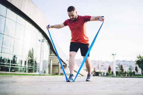 Energetic guy training shoulders with elastic band Stock Photos