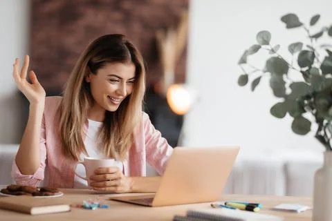 Energetic lady smiling while having a video-call on laptop Stock Photos