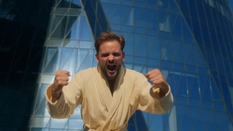Energetic man in bathrobe looking at camera and shouting downtown Stock Footage 318134551