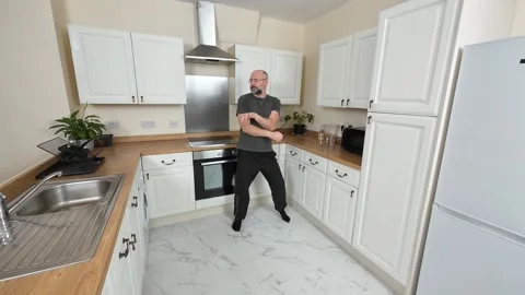 Energetic man joyfully dancing in kitchen, playfully moving hands while swaying Stock Footage 311526690