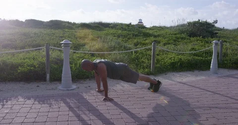 Energetic mature man doing push-ups in the park Stock Footage 116379593