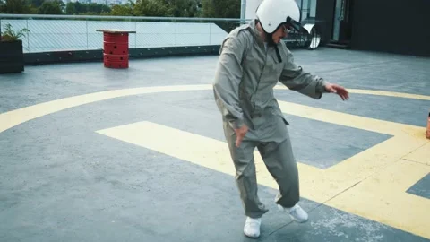 Energetic motorcycle driver in grey overalls, helmet and sunglasses dancing on Stock Footage 138410748