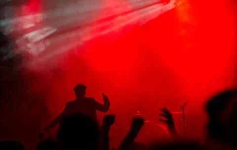 Energetic performance under vibrant red lights captivates audience at live Stock Photos