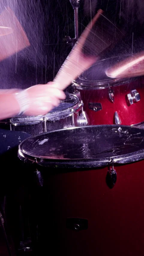 Energetic red drum kit performance with blurred drumstick, wet reflections and Stock Footage 344973155