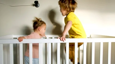 Energetic siblings jumping in crib Stock Footage 128285594