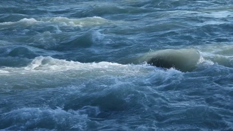 Energetic silty blue river rapids flow over rocks. Close up on churning water. Stock Footage 289549309