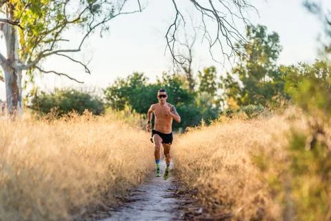Energetic sportsman running on pathway in nature Stock Photos