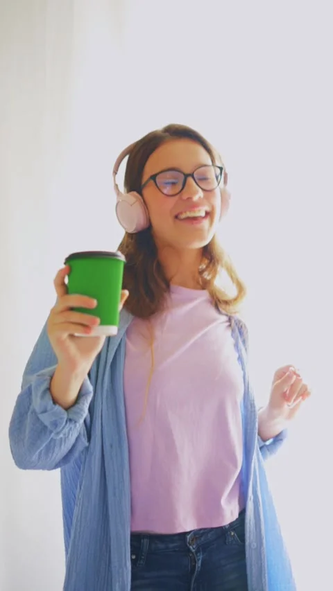Energetic student dancing with coffee and headphones on white background. Stock Footage 312640365