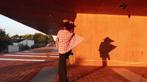 Energetic woman dancing with dramatic shadow in warm sunset light Stock Footage 345029149