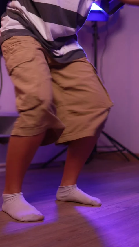 Energetic young girl practices breakdancing in a home studio, illuminated b.. Video stock 305479883