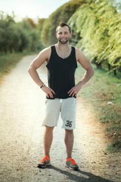 Energetic young man do exercises outdoors and running in park to Stock Photos