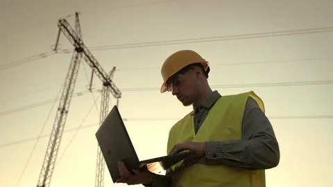 Energy auditor using portable computer during electricity pylon inspection Stock Photos