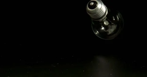 Energy conservation concept. Tungsten light falls and bounces up on black Stock Footage 146452008