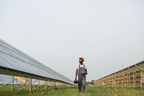 Energy engineer with instruments walking on solar farm Foto stock