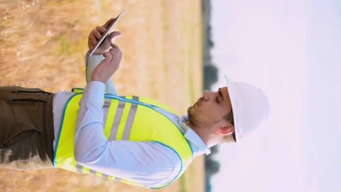 An energy engineer in special clothes inspects a power line using data from elec Stock-Footage 202652154