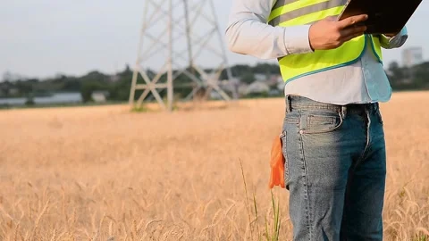 An energy engineer in special clothes inspects a power line using data from elec Stock Footage 202652254