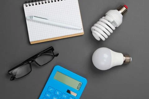 Energy saving analytics. Calculator with light bulbs, notebook on gray backgr Stockfoto's