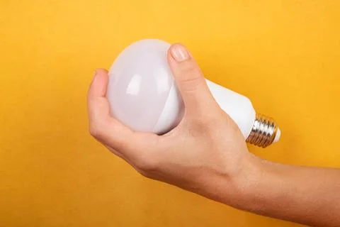 Energy saving concept, led saving lamp in hand on yellow background Stock Photos