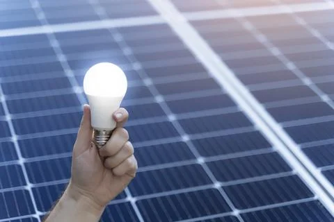 Energy saving concept with a light bulb and solar panels Stock Photos