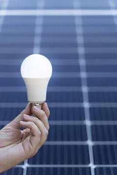 Energy saving concept with a light bulb and solar panels Stock Photos