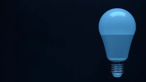 Energy-saving, eco-friendly Led bulb lamp lights up on a black background Vidéo 330884612