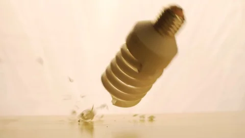 Energy-saving fluorescent light breaks on the surface. The drop to the surface Stock Footage 90403053