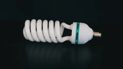 Energy saving fluorescent light bulb on black table Stock Footage 105745223