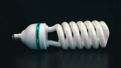 Energy saving fluorescent light bulb on black table Stock Footage 105745243
