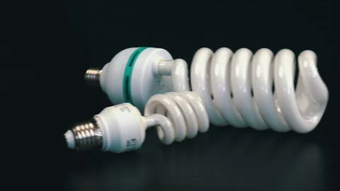 Energy saving fluorescent light bulbs on black table Stock Footage 105745250