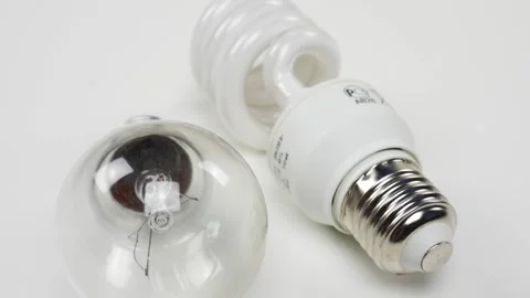 Energy-saving light bulb and a conventional light bulb on a white table Stock Footage 105372000
