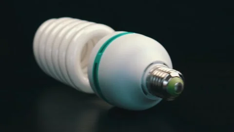 Energy saving light bulb on black table. Camera moves from right to left Stock Footage 105745279