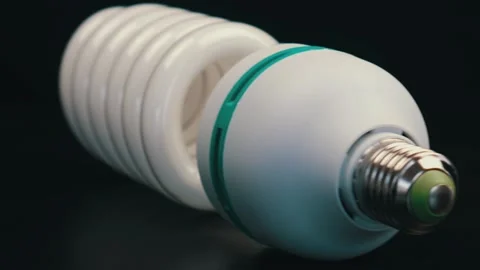 Energy saving light bulb on black table. Camera moves from right to left Stock Footage 105745289