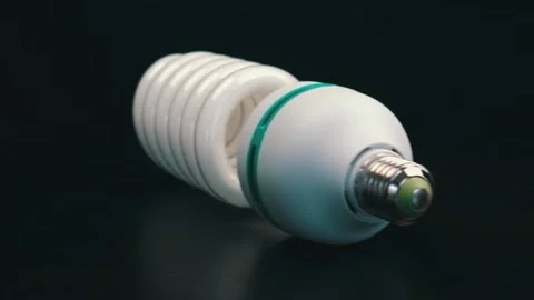 Energy saving light bulb on black table. Camera moves from right to left Stock Footage 105745298