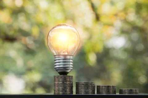 Energy saving light bulb with stacks of coins for saving, financial and accou Stock Photos