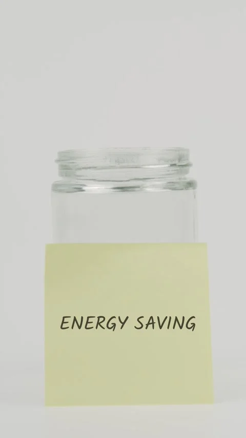 Energy saving text or word on yellow sticky note attached to glass jar Stock Footage 311725713