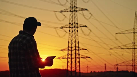 Energy Worker Using Tablet Beneath Power Lines at Sunset 库存影片 344564361