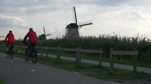 Engaged couple on bicycle with background of windmills in backlight. Video stock 221175206