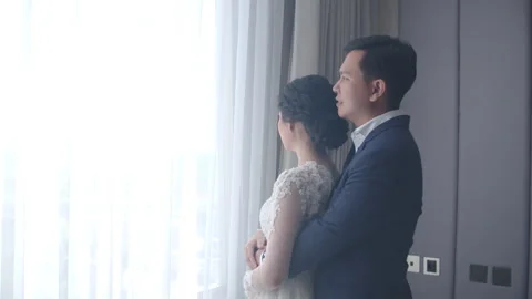 Engaged Couple Looking Out Hotel Window and Embracing Stock Footage 334026864