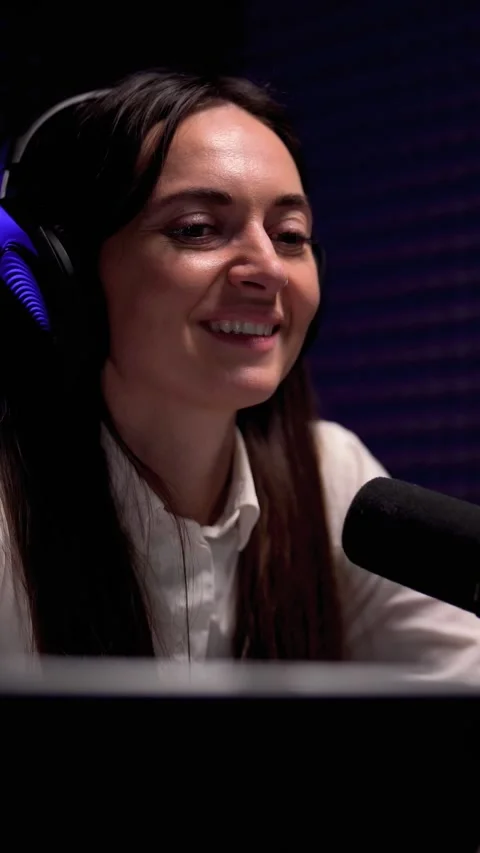 Engaged female interviewee in headphones speaking into microphone. Vertical Stock Footage 235437502