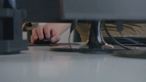 Engaged in focused work at a desk equipped with a computer, mouse, and other Stock Footage 297485348