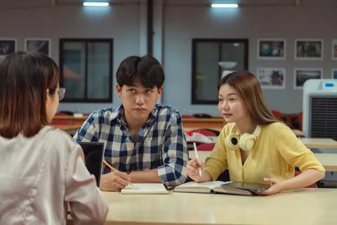 Engaged group of students collaborating over a laptop in a library, Surroun.. Foto stock