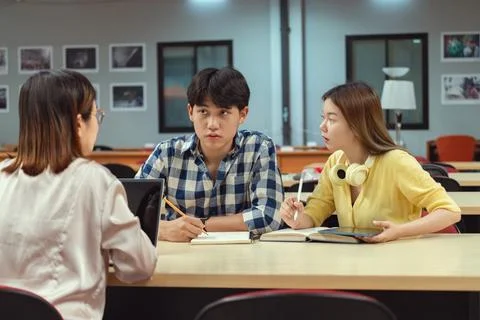 Engaged group of students collaborating over a laptop in a library, Surroun.. Stock Photos
