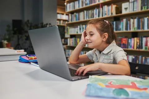 Engaged student doing her homework using laptop in after school club at pri.. Stock Photos
