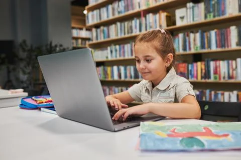 Engaged student doing her homework using laptop in after school club at pri.. Stock Photos