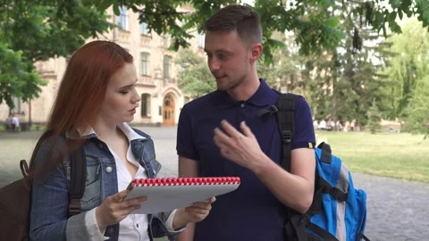 Engaged students sharing ideas over a notebook on campus Stock Footage 311991978