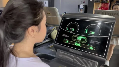Engaged young woman using the treadmill inside a modern fitness center Stock Footage 307796476