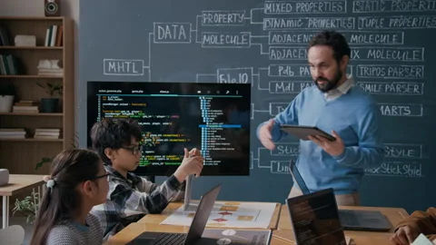 Engaging Coding Teacher Pointing at Algorithm during Lesson in Middle School Stock-Footage 306933371